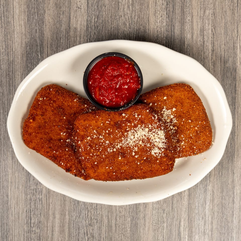 Three breaded fried cutlets topped with grated cheese, served on a white plate with marinara dipping sauce.