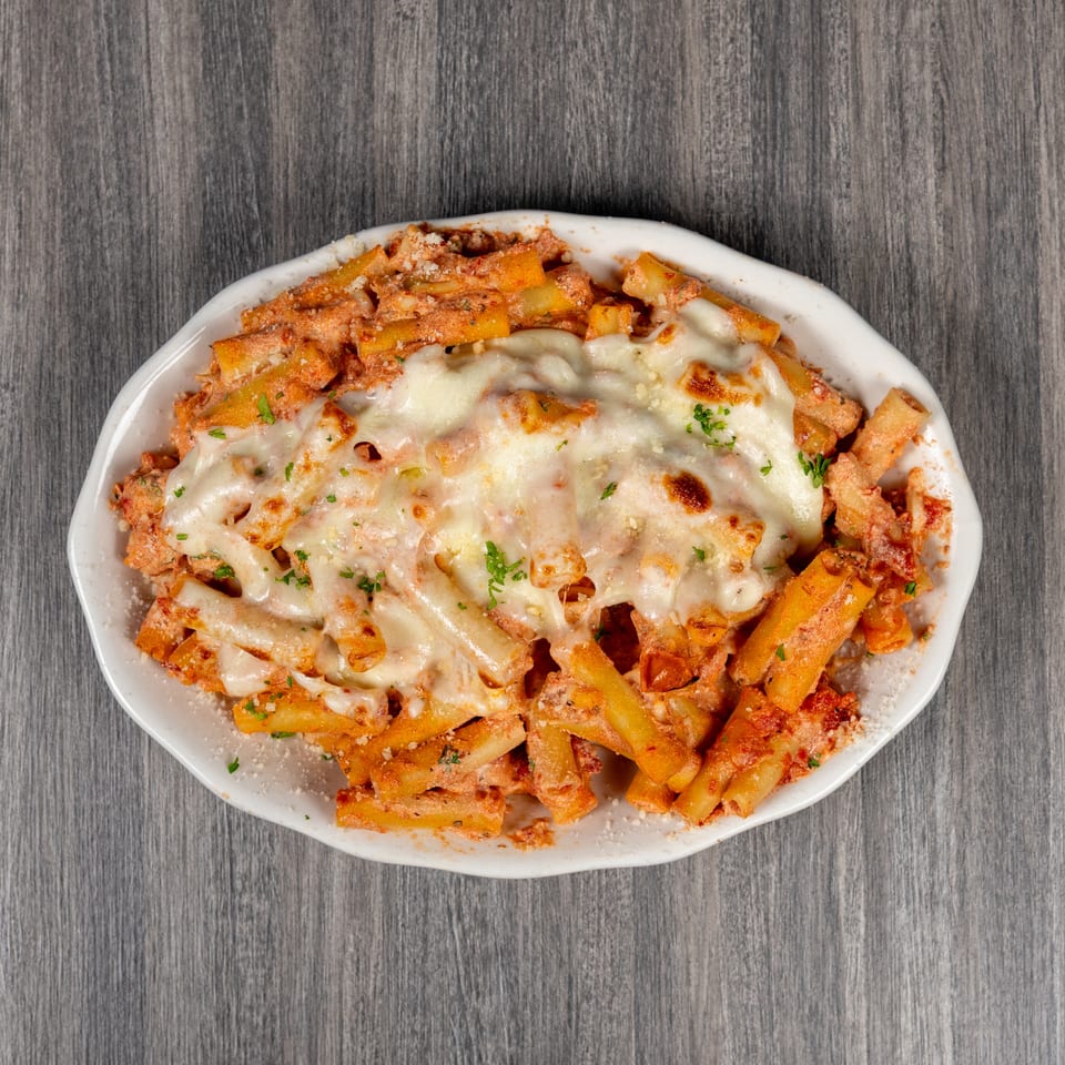 Baked penne pasta in tomato sauce topped with melted cheese and parsley, served on a white oval plate.